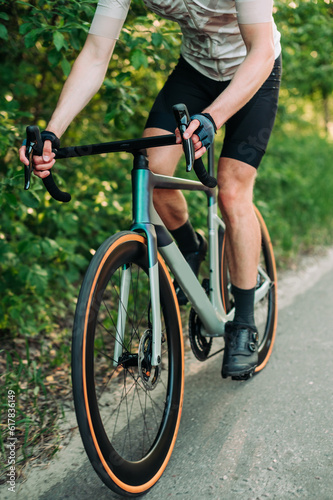 Vertical close-up of a road bike in motion with a cyclist training outside the city. © bodnarphoto