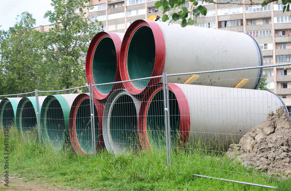 Large diameter pipes are stacked behind a mesh fence Large diameter pipes are stacked behind a mesh fence