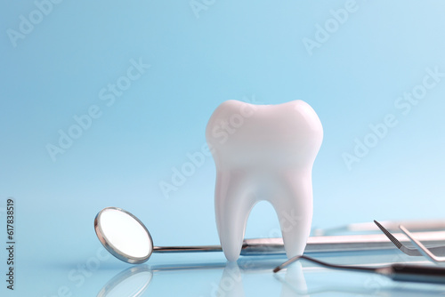 Dentistry concept. Model of a tooth and dental instruments on a colored background with space for text. 