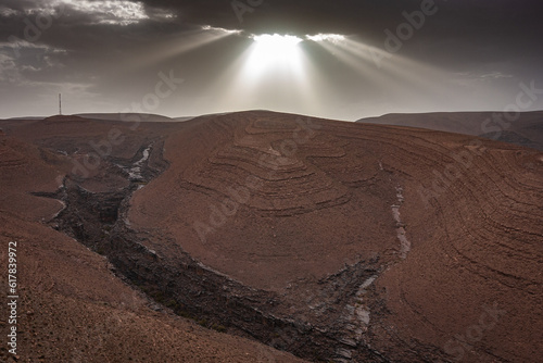 Twilight with the sun behind the clouds, with tracer rays on the desert. The south of Morocco is the land of the Sahara. The south of Morocco is the land of the Sahara. Here, where life is only possib photo