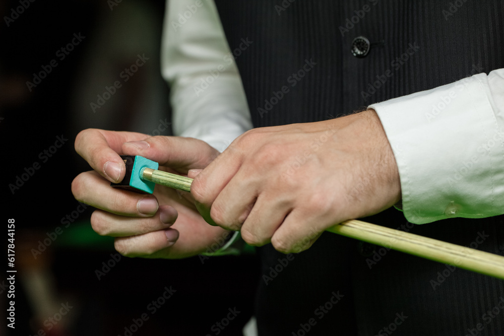 Obraz premium Snooker, billiard player, chalking the cue. closeup view of hands and cue