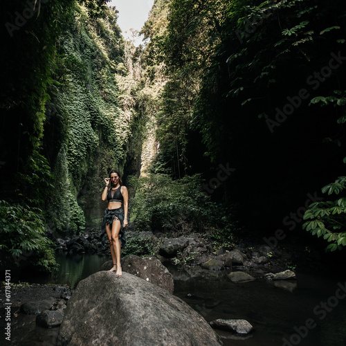Woman stands on a stone in the jungle