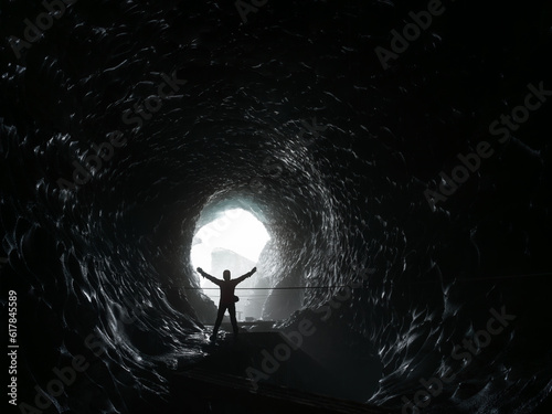 A person standing silouetted, with his arms spread out, inside Katla Ice Cave, Mýrdalsjökull Glacier, South Iceland.