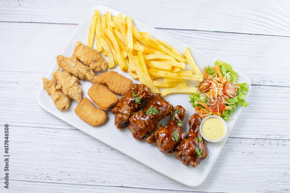 Chicken mix, wings in bbq sauce, nuggets and chicken pieces, accompanied by French fries, salad and mayonnaise