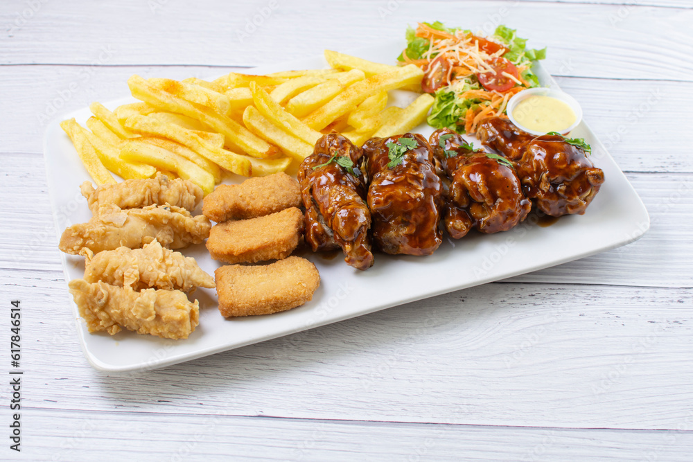 Chicken mix, wings in bbq sauce, nuggets and chicken pieces, accompanied by French fries, salad and mayonnaise