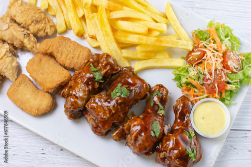 Chicken mix, wings in bbq sauce, nuggets and chicken pieces, accompanied by French fries, salad and mayonnaise