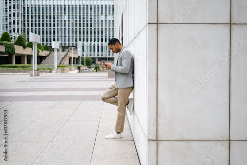 Man using smartphone leaning against wall
