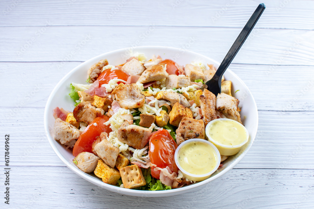 Roasted pork protein salad, accompanied by tomatoes, grated mozzarella cheese, lettuce, bacon, croutons in mayonnaise sauce with mustard