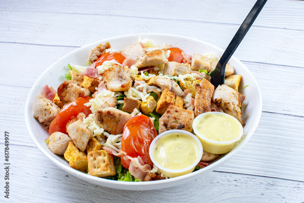 Roasted pork protein salad, accompanied by tomatoes, grated mozzarella cheese, lettuce, bacon, croutons in mayonnaise sauce with mustard