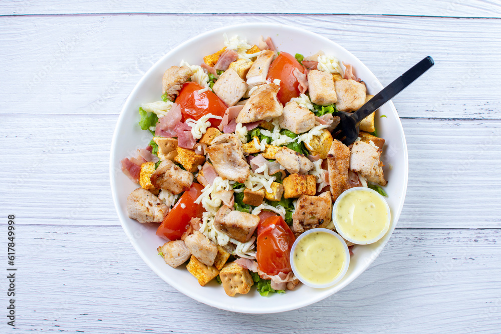 Bowl salad with pieces of roasted pork, grated cheese, beans, corn, tomato, nachos, lettuce, with house mayonnaise