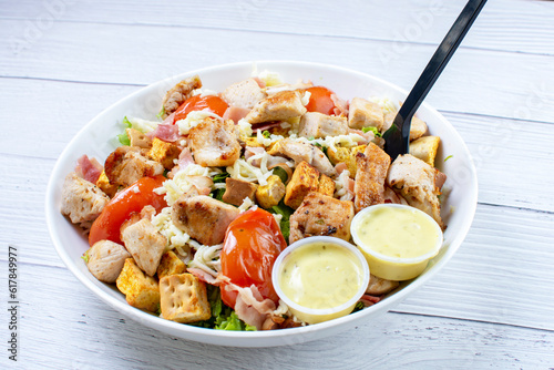 Obraz na płótnie Roasted pork protein salad, accompanied by tomatoes, grated mozzarella cheese, lettuce, bacon, croutons in mayonnaise sauce with mustard w salonie