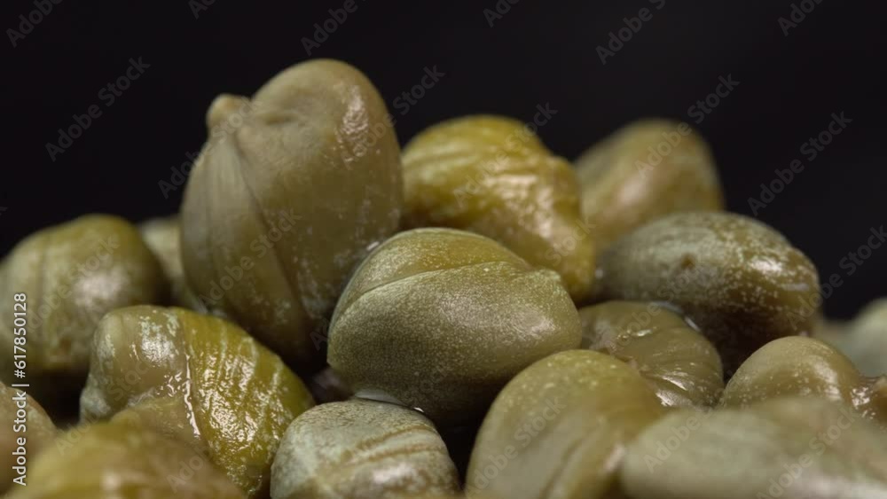 Pickled marinated capers rotate on a black background. Ingredients for making spicy sauce, tartare or salad Pickled marinated capers rotate on a black background. Ingredients for making spicy sauce, tartare or salad