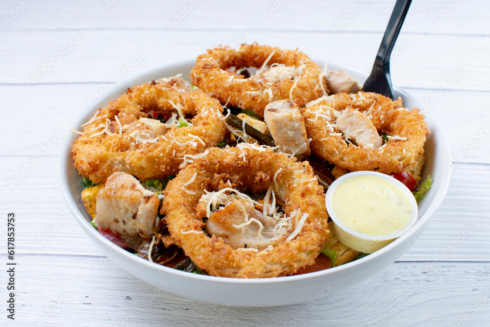 Bowl salad with pieces of roast pork, grated cheese, onion rings and house mayonnaise