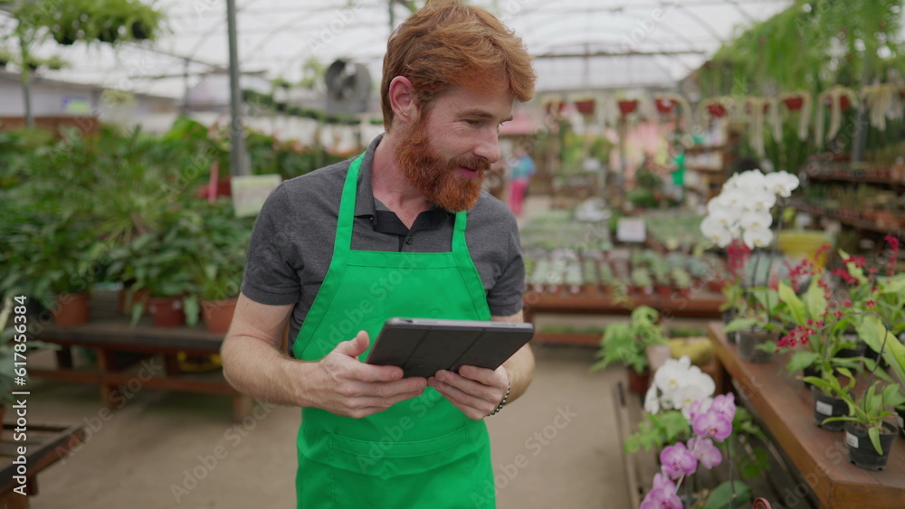 Mobile Male Employee Checking Inventory via Tablet in Flower Shop. Green Aproned Young Man Integrating Modern Tech in Store Operations Mobile Male Employee Checking Inventory via Tablet in Flower Shop. Green Aproned Young Man Integrating Modern Tech in Store Operations