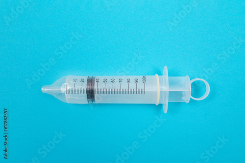Safe Vaccine, Anti Vaccination Concept - Syringe in a Condom Lay on Blue Table in Clinic or Hospital. Mistrust of Vaccination. Natural Immunity. Skepticism About the Vaccine. Freedom and Human Rights