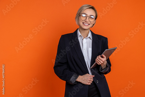Confident satisfied woman wearing black official style suit standing with tablet looking at camera