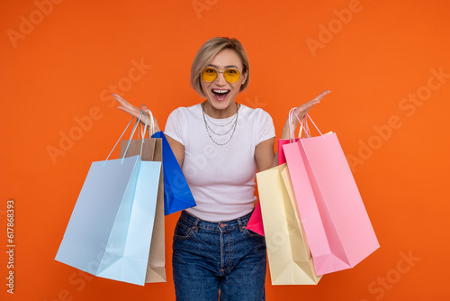 Overjoyed woman in white t shirt and jeans standing with shoppingbags rejoicing photo