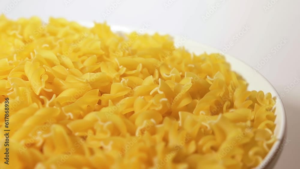 Uncooked Fusilli Pasta on White Plate Rotating against White Background. Fat and Unhealthy Food. Dry Spiral Macaroni. Italian Culture and Cuisine. Raw Golden Pasta Uncooked Fusilli Pasta on White Plate Rotating against White Background. Fat and Unhealthy Food. Dry Spiral Macaroni. Italian Culture and Cuisine. Raw Golden Pasta