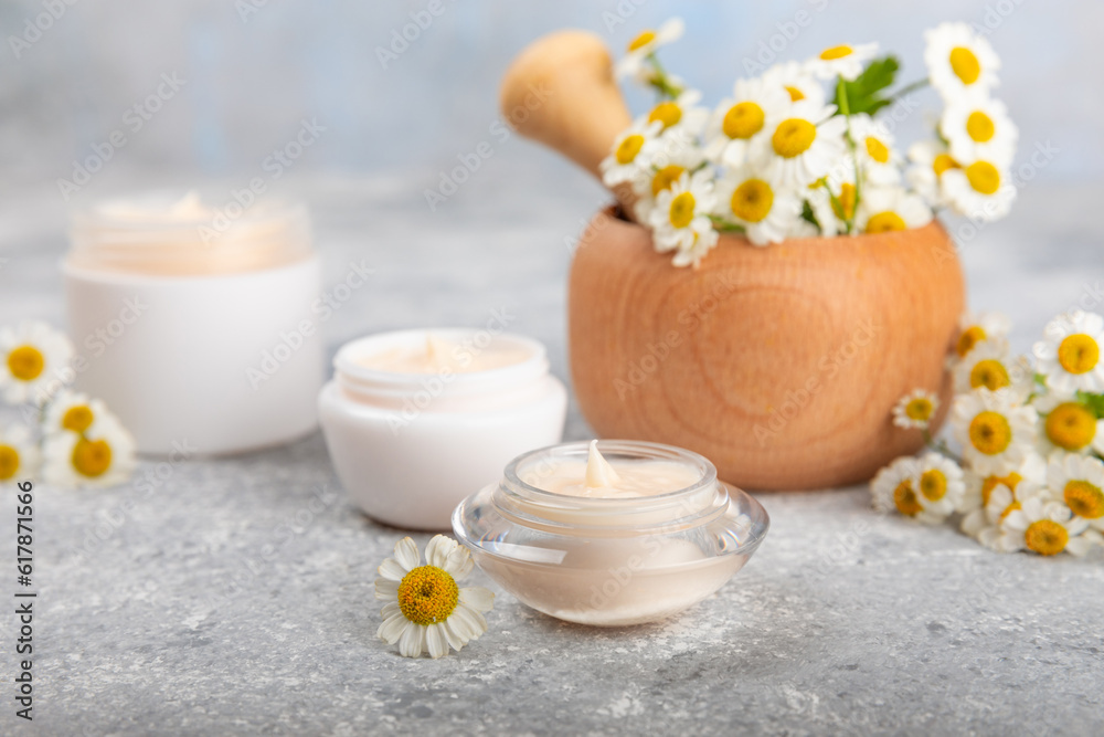 Body and hand cream with chamomile flower on a concrete background. Herbal dermatological cosmetic hygiene cream. Natural cosmetic product. Cosmetic tube. Ecological cosmetics.Copy space.