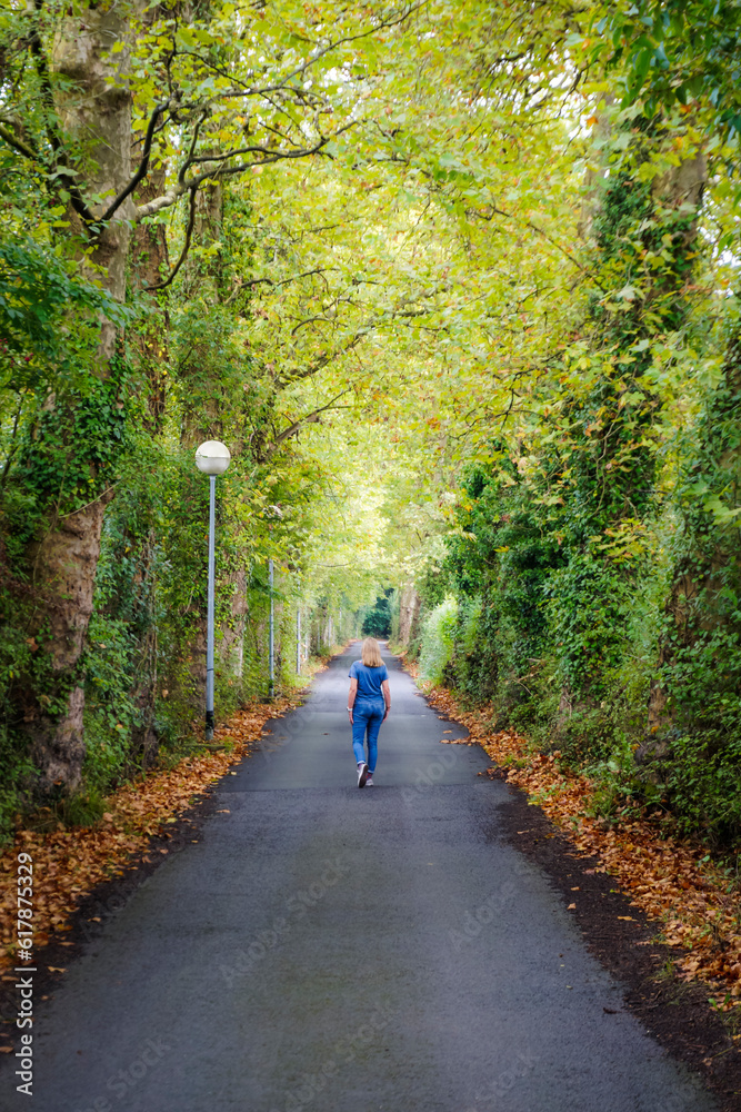 Young woman dressed in blue clothing walking along a path surrounded by vegetation Young woman dressed in blue clothing walking along a path surrounded by vegetation