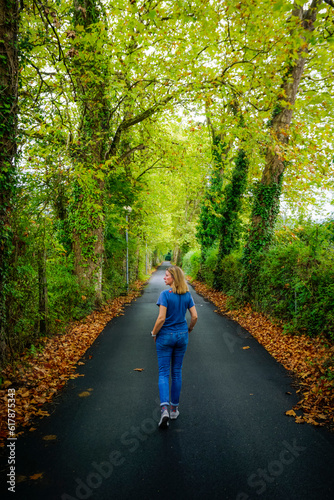 Young woman dressed in blue clothing walking along a path surrounded by vegetation