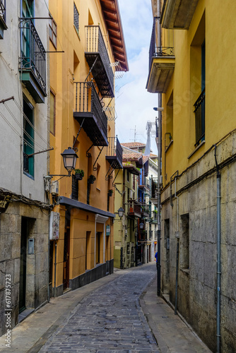 Narrow street of a town with colorful buildings and flowers on the balconies