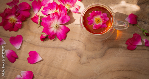 pink rose petals and cup of tea on wooden background