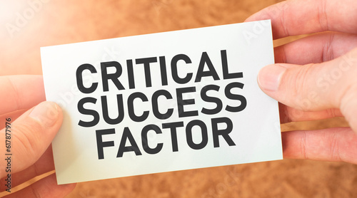 CRITICAL SUCCESS FACTOR word inscription on white card paper sheet in hands of a businessman. recap concept. red and white paper