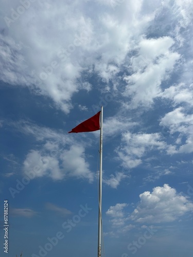 red beach flag with clouds and blue sky