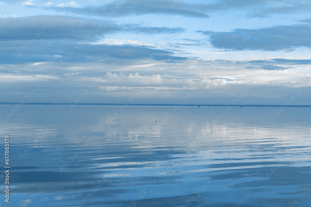 White blue clouds over lake, symmetric sky and water background, cloudscape on lake. Nature abstract, cloudy sky reflected on water, calm tranquil concept, aesthetic panoramic view