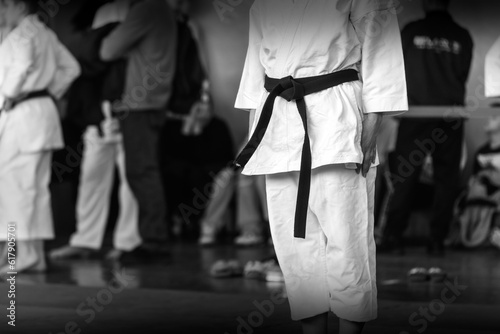 A martial arts athlete in a white kimano with a black belt is preparing for a fight. Black and white photo with motion blur effect.