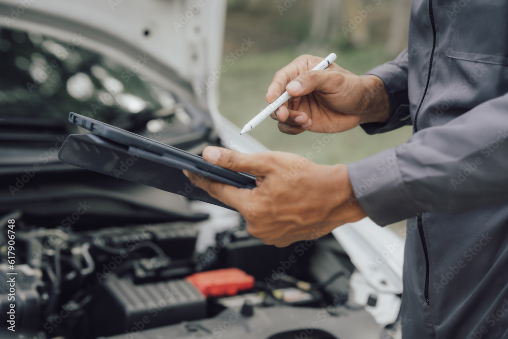 Young mechanic opens the bonnet to inspect the engine for damage and does professional maintenance. He puts on his uniform and inspects. Young mechanic opens the bonnet to inspect the engine for damage and does professional maintenance. He puts on his uniform and inspects.