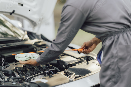 A car mechanic checks and maintains the engine for the customer. The car hood and master inspector replace the damaged parts in the car while checking the operation of the car. repair concept service