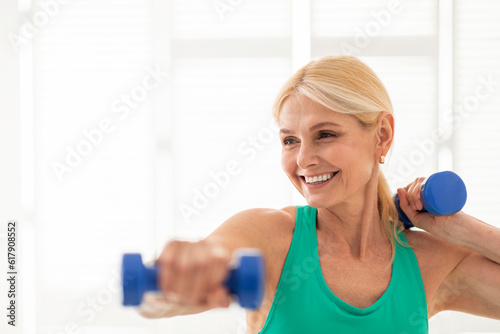 Portrait Of Happy Beautiful Mature Woman Holding Dumbbells In Hands