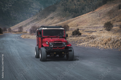 Close up shot of driving red jeep on Bromo road. Rental off road vehicle for exploring mountain volcano reservation © Flash Vector