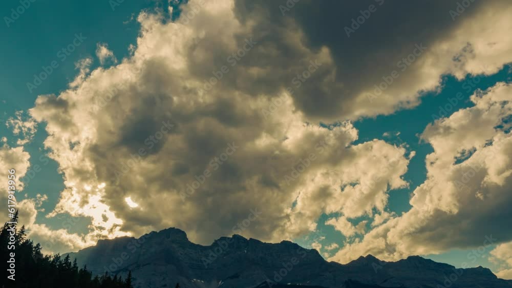 abstract clouds sky about silhouette cloudscape time-lapse. pastel blue sky bright sun rays beams through  clouds above a mountain in sunset time. sun down at the peak of the mountain. cloudy weather