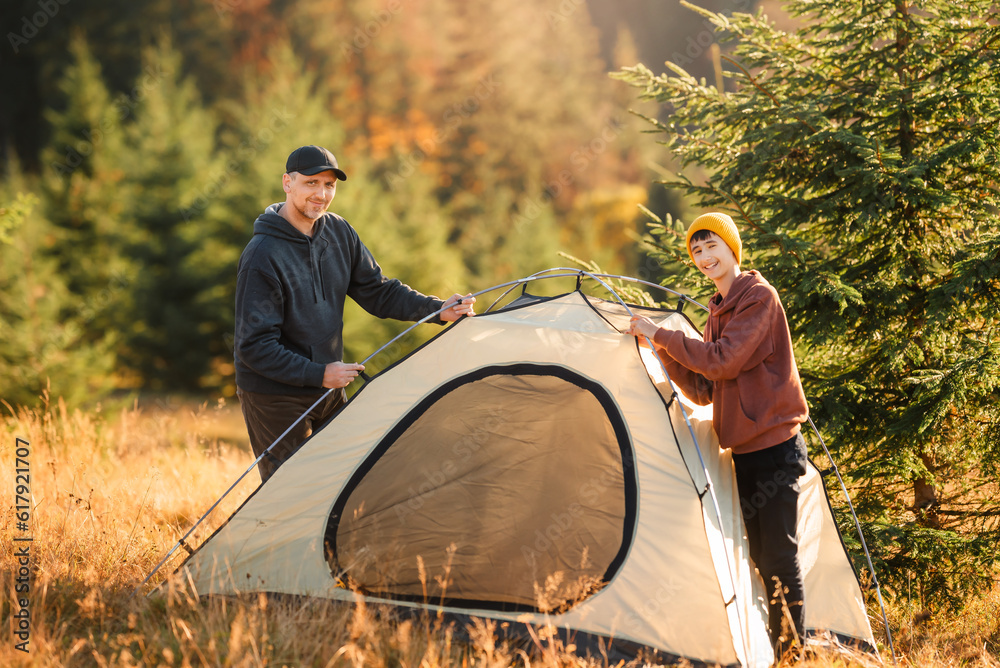 Obraz na plátně Father and son set up a tourist tent in a camp