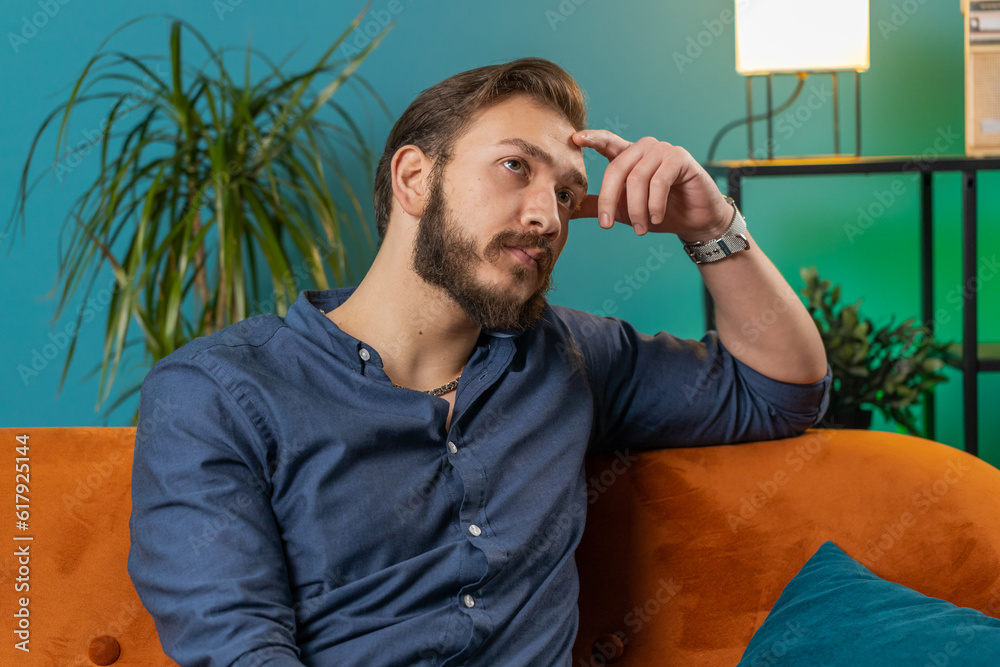 Sad lonely man sitting at home room looks pensive thinks over life ...