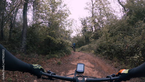 Riding a mountain bike from rider point of view on the handlebar on a gravel dusty and muddy single track trail