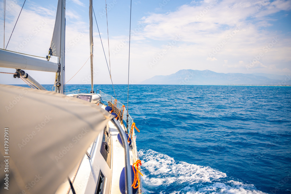 Fototapeta premium Yacht sailing in an open sea. Close-up view of side of the boat. Clear sky after the rain, waves and water splashes
