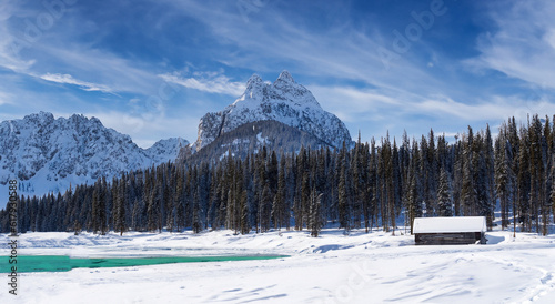 amazing cabin in the middle of a large snow filled lake with large mountains in the background