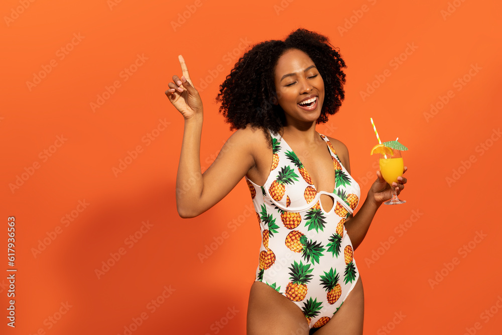 Joyful pretty black woman in colorful one-piece swimsuit drinking cocktail Joyful pretty black woman in colorful one-piece swimsuit drinking cocktail