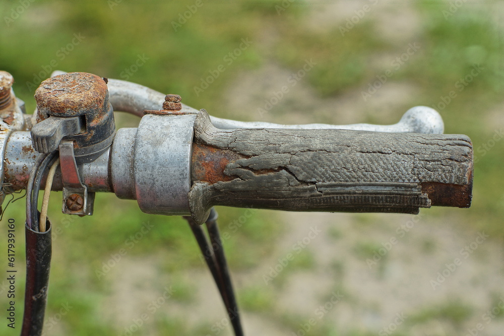 very old cracked rubber throttle stick with a metal lever and part of the steering wheel of a retro non-working motorcycle outdoors during the day very old cracked rubber throttle stick with a metal lever and part of the steering wheel of a retro non-working motorcycle outdoors during the day