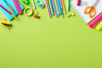 Back to school concept. Frame border made of school supplies on green background.