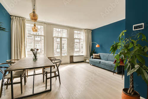 a living room with blue walls and hardwood flooring, including a wooden dining table surrounded by two planters