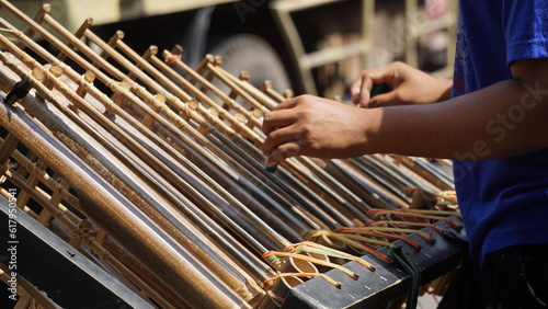 A man is playing angklung. That is a multitonal musical instrument that developed from the Sundanese people. Angklung is made of bamboo photo