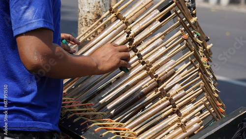 A man is playing angklung. That is a multitonal musical instrument that developed from the Sundanese people. Angklung is made of bamboo photo