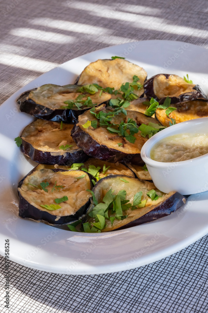 Plateful of Fried Sliced Aubergine or Eggplant Covered with Fresh Flat Leaf Parsley and Served with Pureed Roasted Garlic Plateful of Fried Sliced Aubergine or Eggplant Covered with Fresh Flat Leaf Parsley and Served with Pureed Roasted Garlic