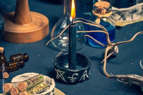 Witchcraft altar selective focus to details of candles light and magic tools or items.  Halloween and occult black magic ritual. Magic practice symbolism. Ritual scene in dark frightening atmosphere.