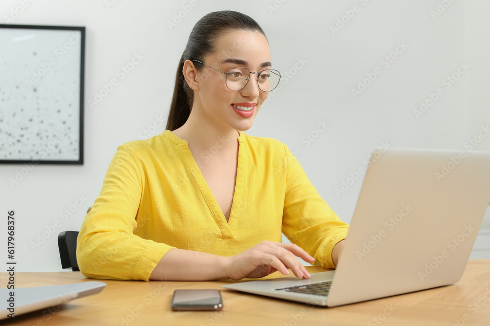 Home workplace. Happy woman working on laptop at wooden desk in room Home workplace. Happy woman working on laptop at wooden desk in room